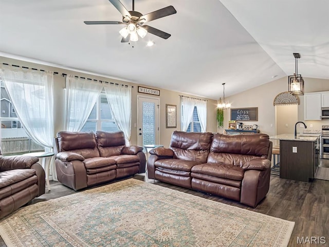 living area featuring vaulted ceiling, a chandelier, a ceiling fan, and dark wood-type flooring