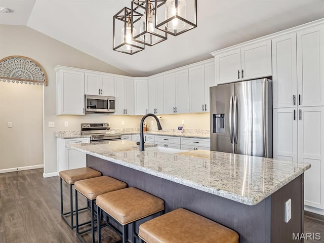 kitchen with appliances with stainless steel finishes, a sink, lofted ceiling, dark wood-style flooring, and white cabinets
