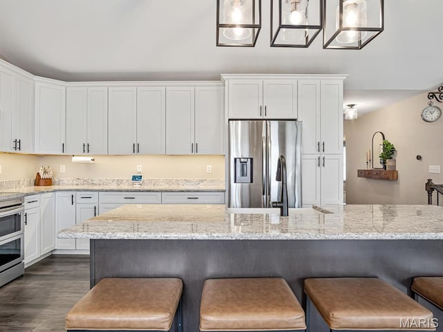 kitchen with stainless steel appliances, white cabinets, a breakfast bar area, and dark wood-style flooring