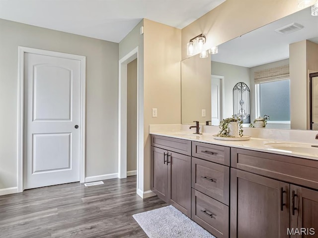 full bathroom with double vanity, wood finished floors, and baseboards