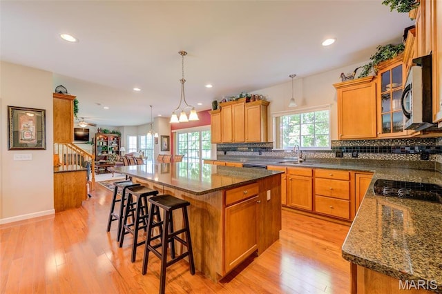 41 Deer Creek Dr, Ofallon, MO 63366 - kitchen with a sink, stainless steel microwave, a center island, decorative backsplash, and light wood-style flooring
