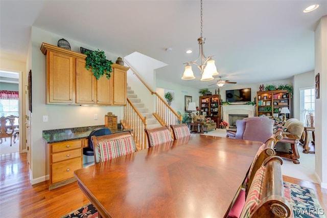 41 Deer Creek Dr, Ofallon, MO 63366 - dining area with a chandelier, a fireplace, recessed lighting, ceiling fan, and light wood-type flooring