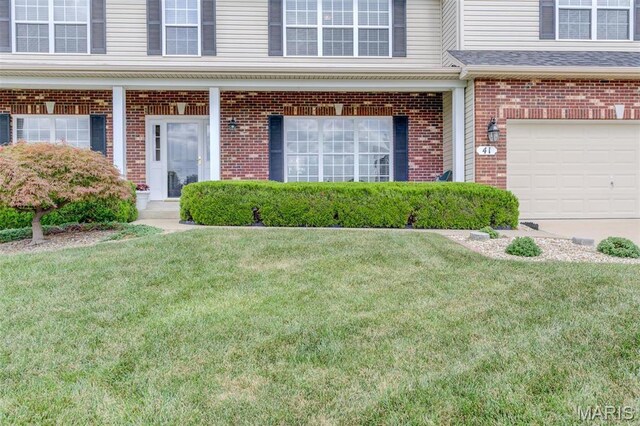 41 Deer Creek Dr, Ofallon, MO 63366 - view of exterior entry featuring brick siding, a lawn, and a garage