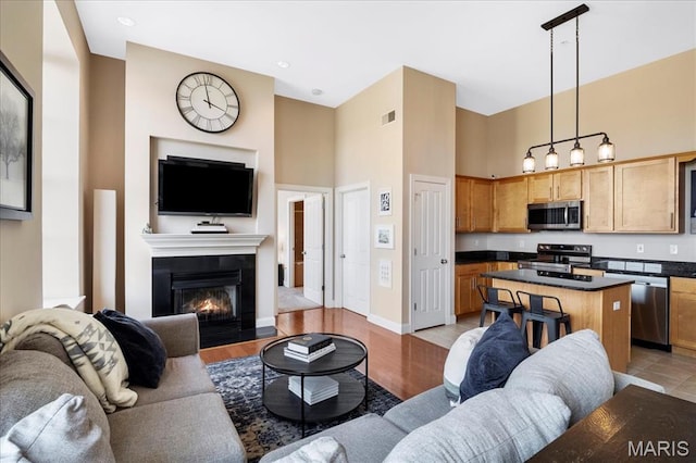living area with a towering ceiling, a fireplace with flush hearth, and baseboards