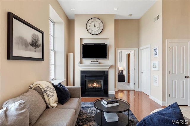 living area featuring a glass covered fireplace, wood finished floors, and baseboards