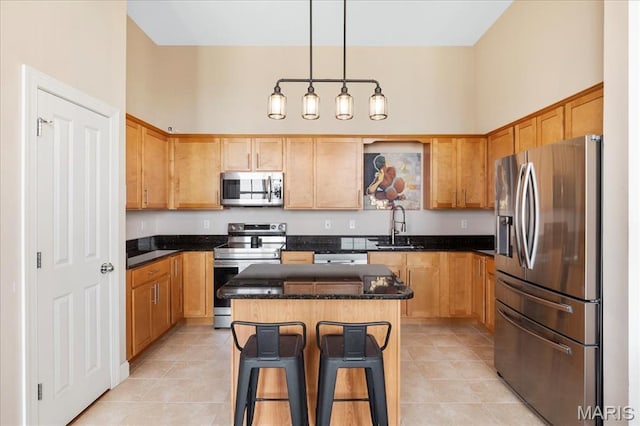 kitchen featuring appliances with stainless steel finishes, a sink, light tile patterned floors, and a breakfast bar