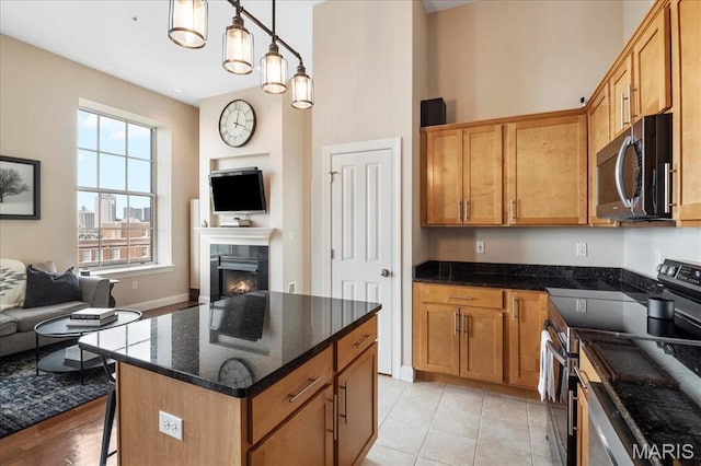 kitchen with stainless steel appliances, open floor plan, a breakfast bar area, a lit fireplace, and a high ceiling