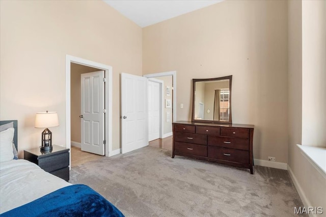 bedroom with light colored carpet, a high ceiling, and baseboards