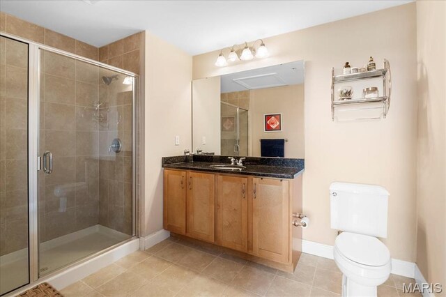 full bath featuring a stall shower, baseboards, toilet, and vanity