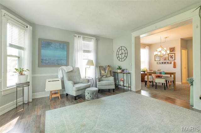 sitting room with wood finished floors, healthy amount of natural light, a chandelier, and baseboards
