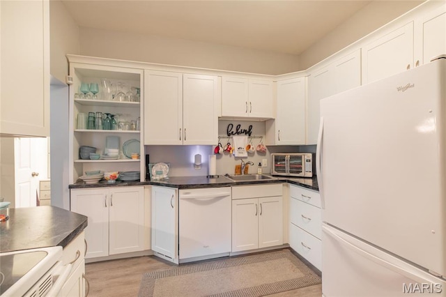 kitchen with white appliances, a sink, white cabinets, and dark countertops