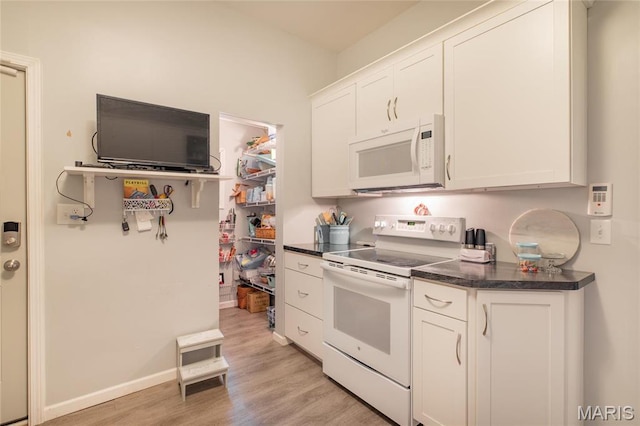 kitchen with white appliances, dark countertops, light wood-type flooring, and white cabinets