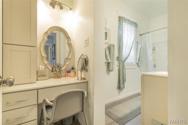 bathroom with a shower with shower curtain, vanity, and baseboards