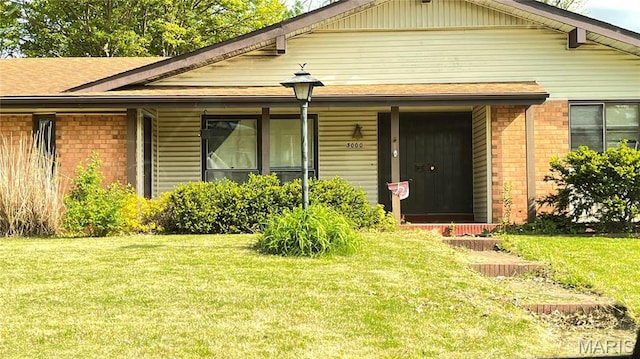3000 Chadwick Dr, Florissant, MO 63033 - view of front of property with brick siding, a front yard, and a porch