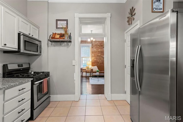 111 Portland Ave, Belleville, IL 62220 - kitchen with stainless steel appliances, white cabinets, light tile patterned flooring, baseboards, and light stone counters