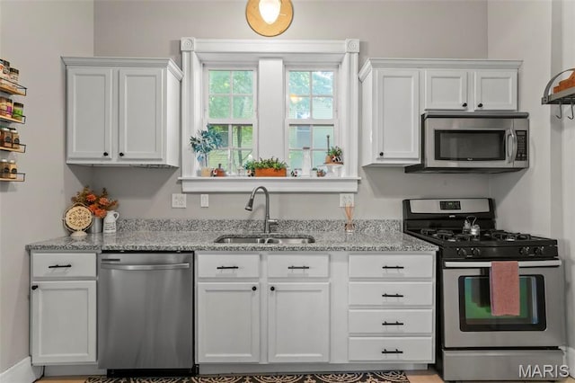 111 Portland Ave, Belleville, IL 62220 - kitchen featuring stainless steel appliances, a sink, white cabinetry, and light stone counters