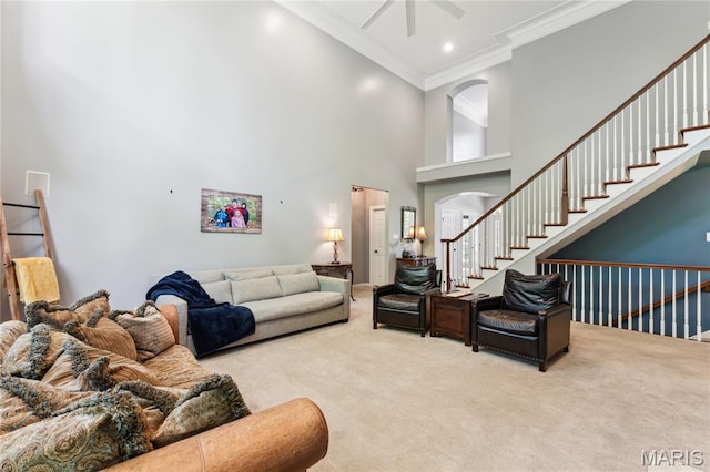 living room with carpet flooring, crown molding, a towering ceiling, ceiling fan, and arched walkways