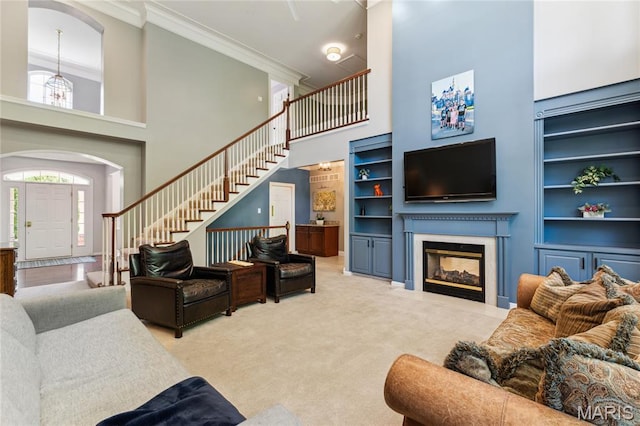living room with a high ceiling, stairs, crown molding, built in features, and carpet floors