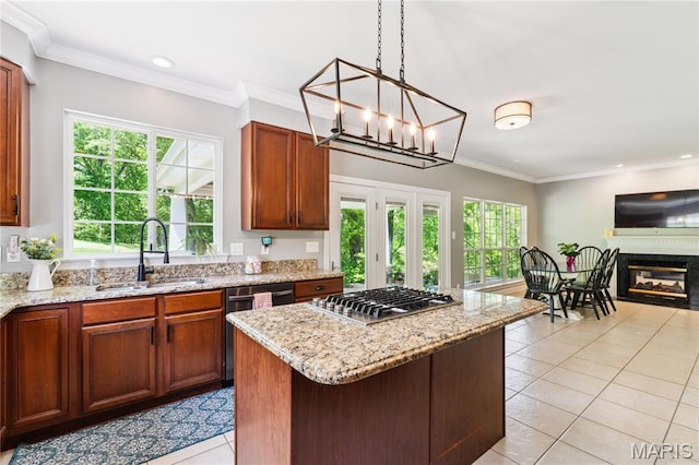 kitchen featuring appliances with stainless steel finishes, a sink, light tile patterned floors, light stone counters, and plenty of natural light