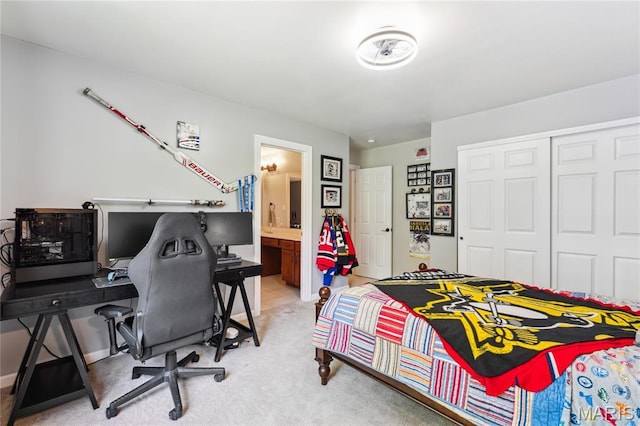 bedroom with a closet, light carpet, a desk, and ensuite bathroom