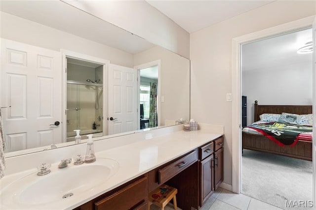 ensuite bathroom featuring a shower with door, tile patterned floors, and vanity