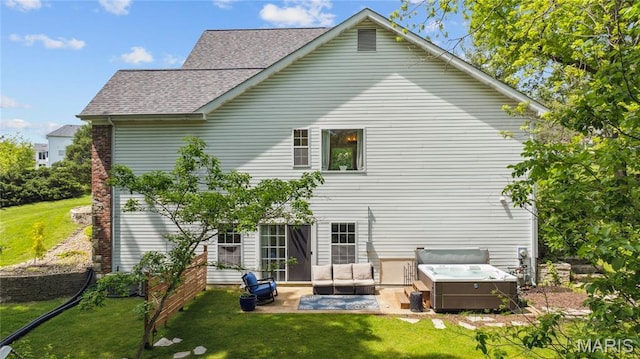 back of house featuring a hot tub, a patio area, a yard, and roof with shingles
