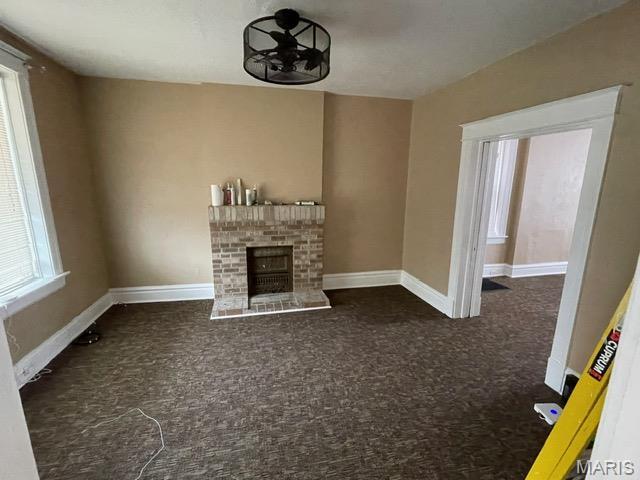 unfurnished living room featuring carpet flooring, baseboards, and a brick fireplace