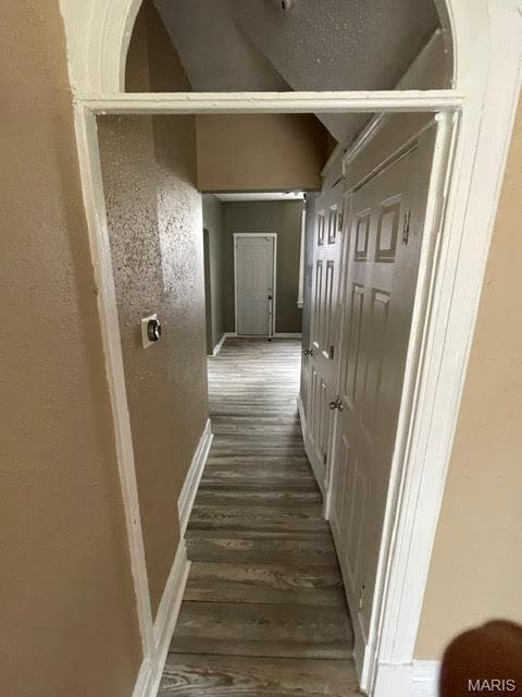 hallway with dark wood-type flooring and baseboards
