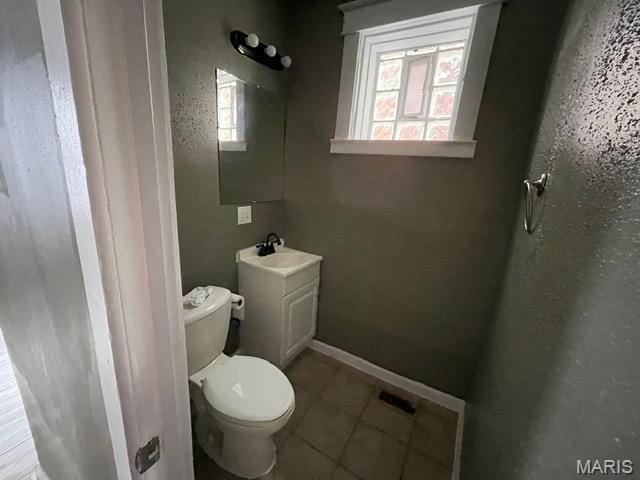 half bath featuring toilet, tile patterned floors, and vanity