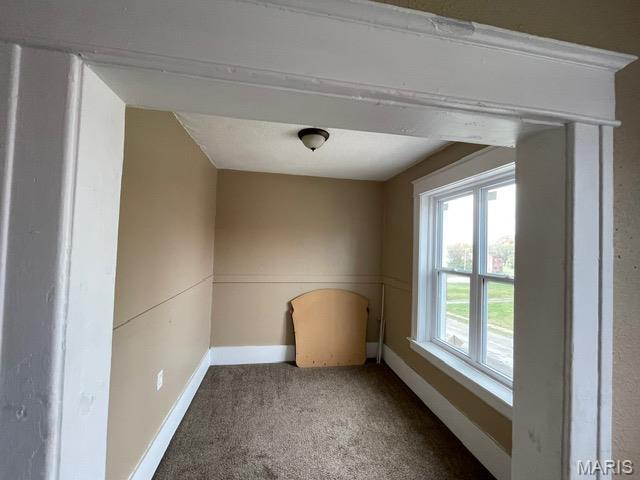 carpeted spare room featuring baseboards