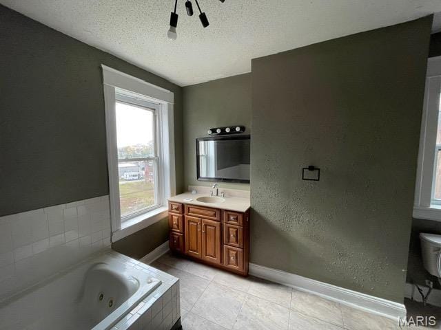 bathroom with baseboards, a textured ceiling, a whirlpool tub, vanity, and tile patterned floors