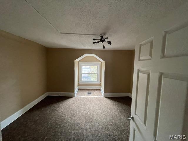 additional living space featuring carpet flooring, a textured ceiling, and baseboards