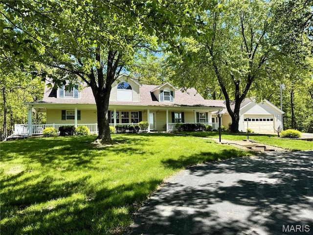 new england style home with covered porch, a front lawn, and driveway