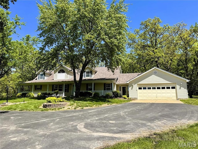 view of front facade featuring asphalt driveway, a garage, covered porch, and a front yard