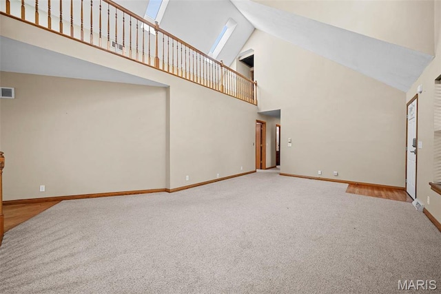 unfurnished living room featuring carpet floors, high vaulted ceiling, and baseboards