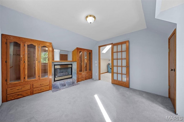 unfurnished living room featuring vaulted ceiling, carpet floors, and a tile fireplace