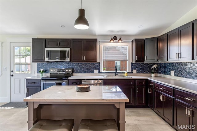 946 Weber Rd, Farmington, MO 63640 - kitchen featuring stainless steel appliances, a sink, tasteful backsplash, hanging light fixtures, and light stone counters