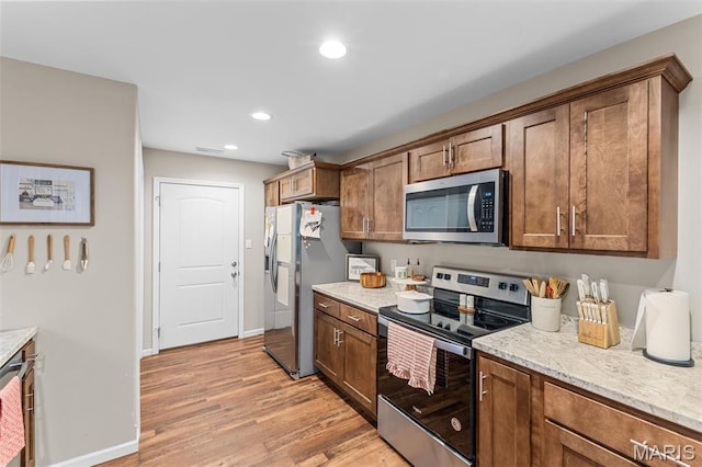 710 Skye View Ct, Farmington, MO 63640 - kitchen with stainless steel appliances, light wood-type flooring, brown cabinetry, recessed lighting, and light stone counters