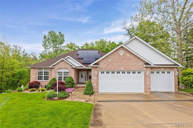ranch-style house with concrete driveway, brick siding, a front yard, roof mounted solar panels, and an attached garage