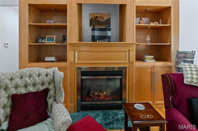 sitting room featuring built in shelves and a glass covered fireplace