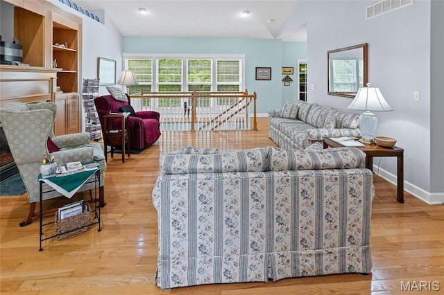 living area featuring vaulted ceiling, baseboards, and wood finished floors