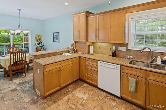 kitchen with dishwasher, a sink, a peninsula, backsplash, and light stone countertops
