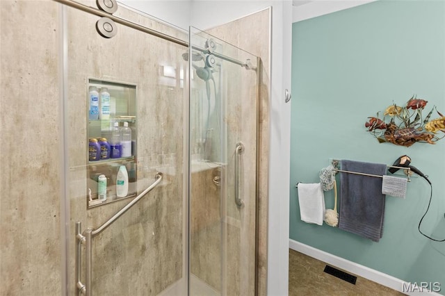 bathroom with a shower stall and baseboards