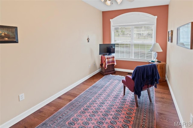 sitting room featuring wood finished floors, baseboards, and arched walkways