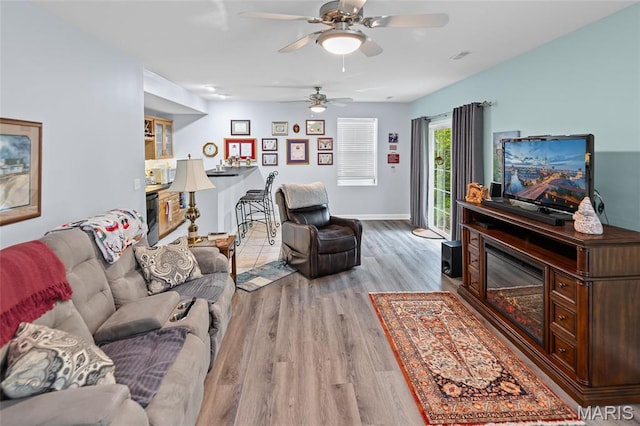 living area featuring wood finished floors, ceiling fan, and baseboards
