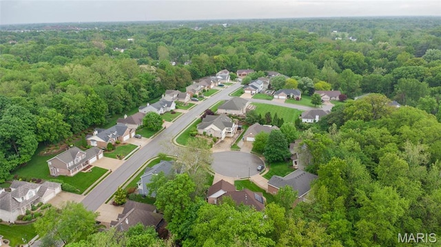 view of property location featuring nearby suburban area and a heavily wooded area