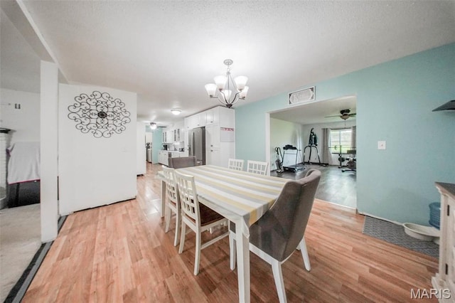 dining space featuring a chandelier, light wood-type flooring, and a ceiling fan