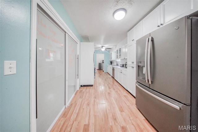 kitchen featuring stainless steel refrigerator with ice dispenser, white cabinets, light wood finished floors, and a textured ceiling