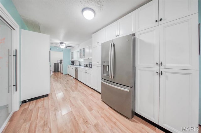 kitchen featuring stainless steel appliances, white cabinets, light wood-type flooring, ceiling fan, and a sink