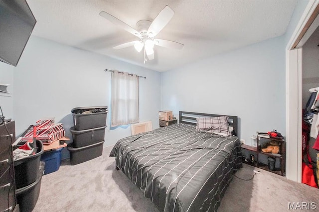 carpeted bedroom featuring a ceiling fan and a textured ceiling